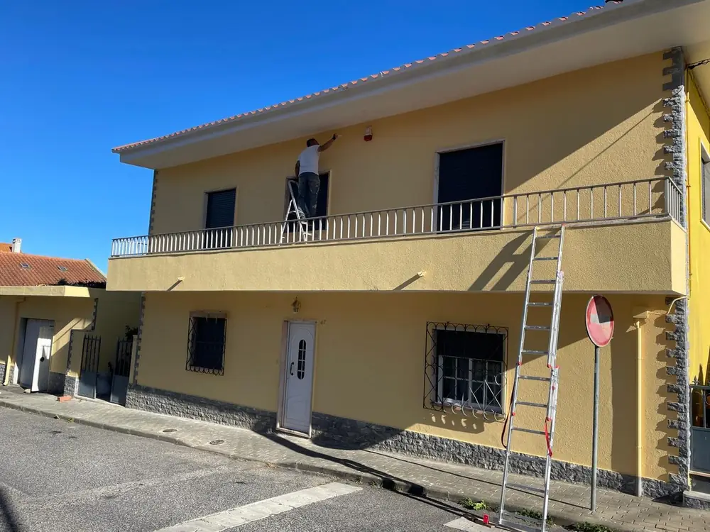 Equipa da Rabisco Boreal a pintar a fachada de uma moradia